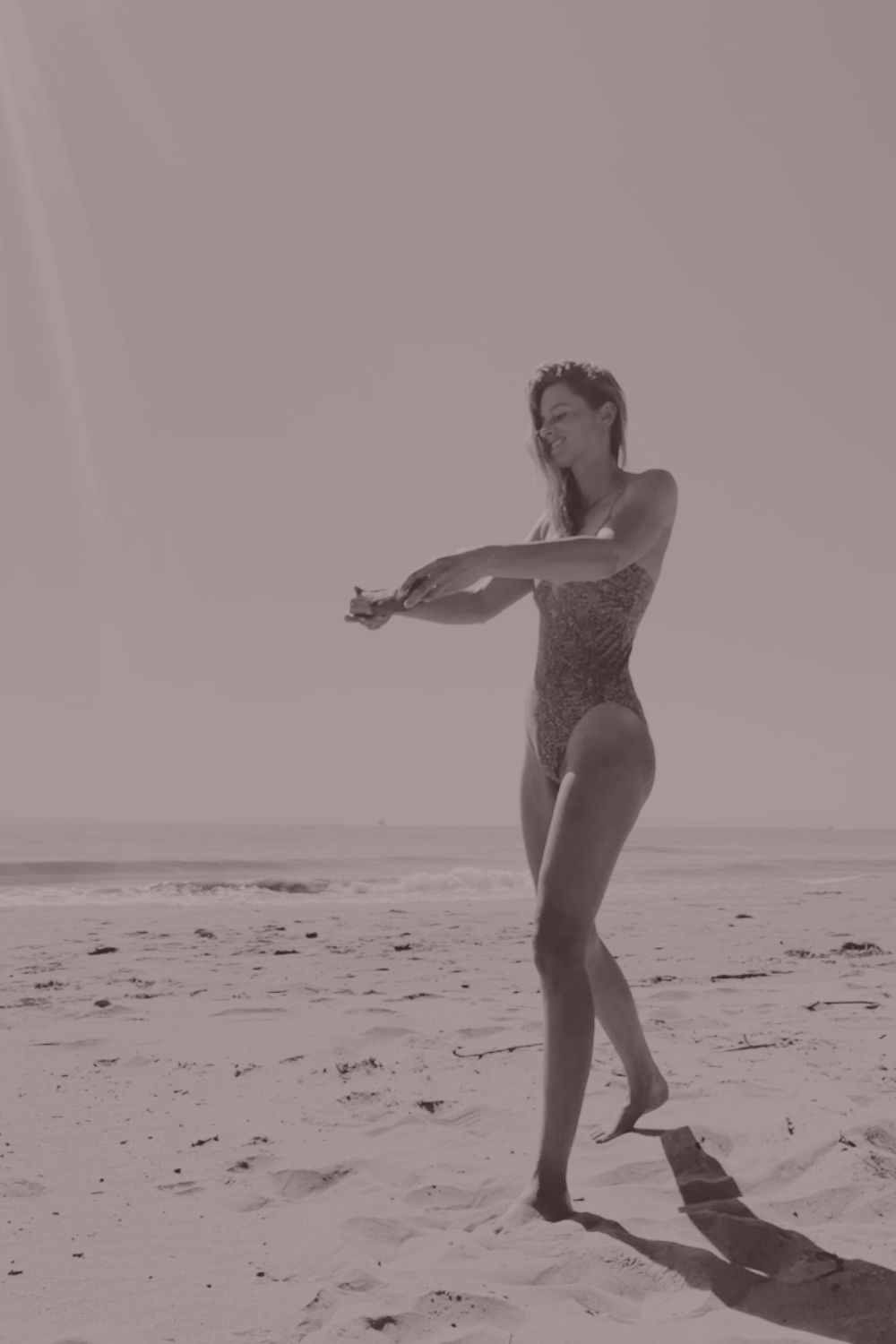 A woman standing barefoot at the ocean's edge