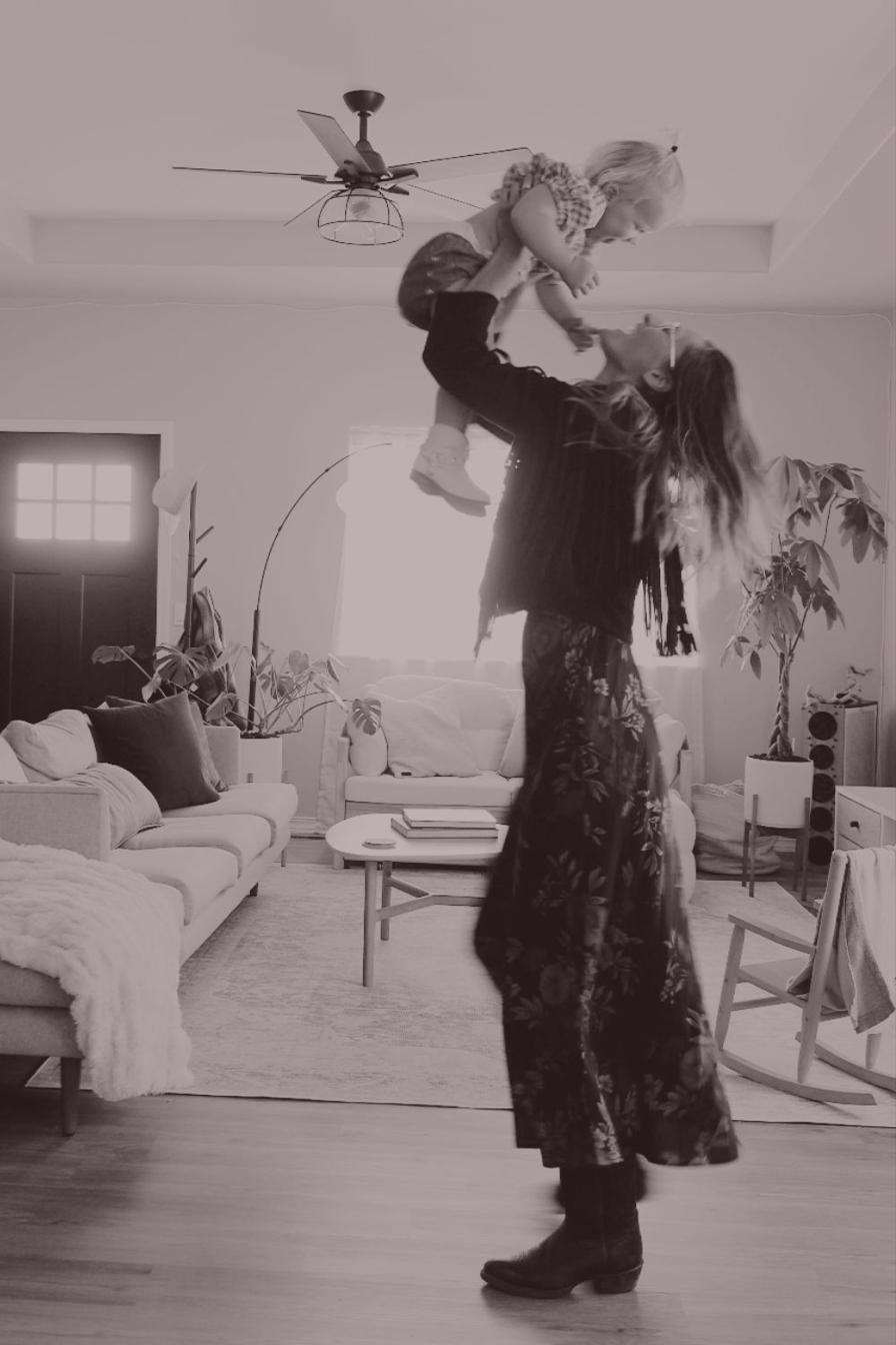 Rita lifting her daughter joyfully in the air at home