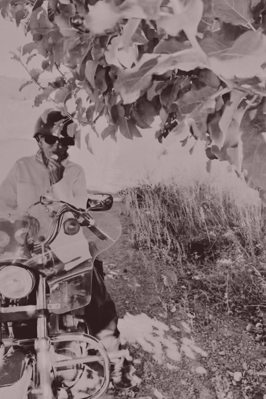 Rita's mother seated on her motorcycle beneath an apple tree