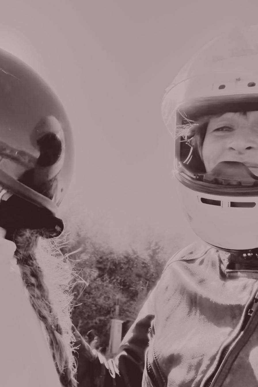 Rita and her mother laughing together in motorcycle helmets, her mother's braid visible