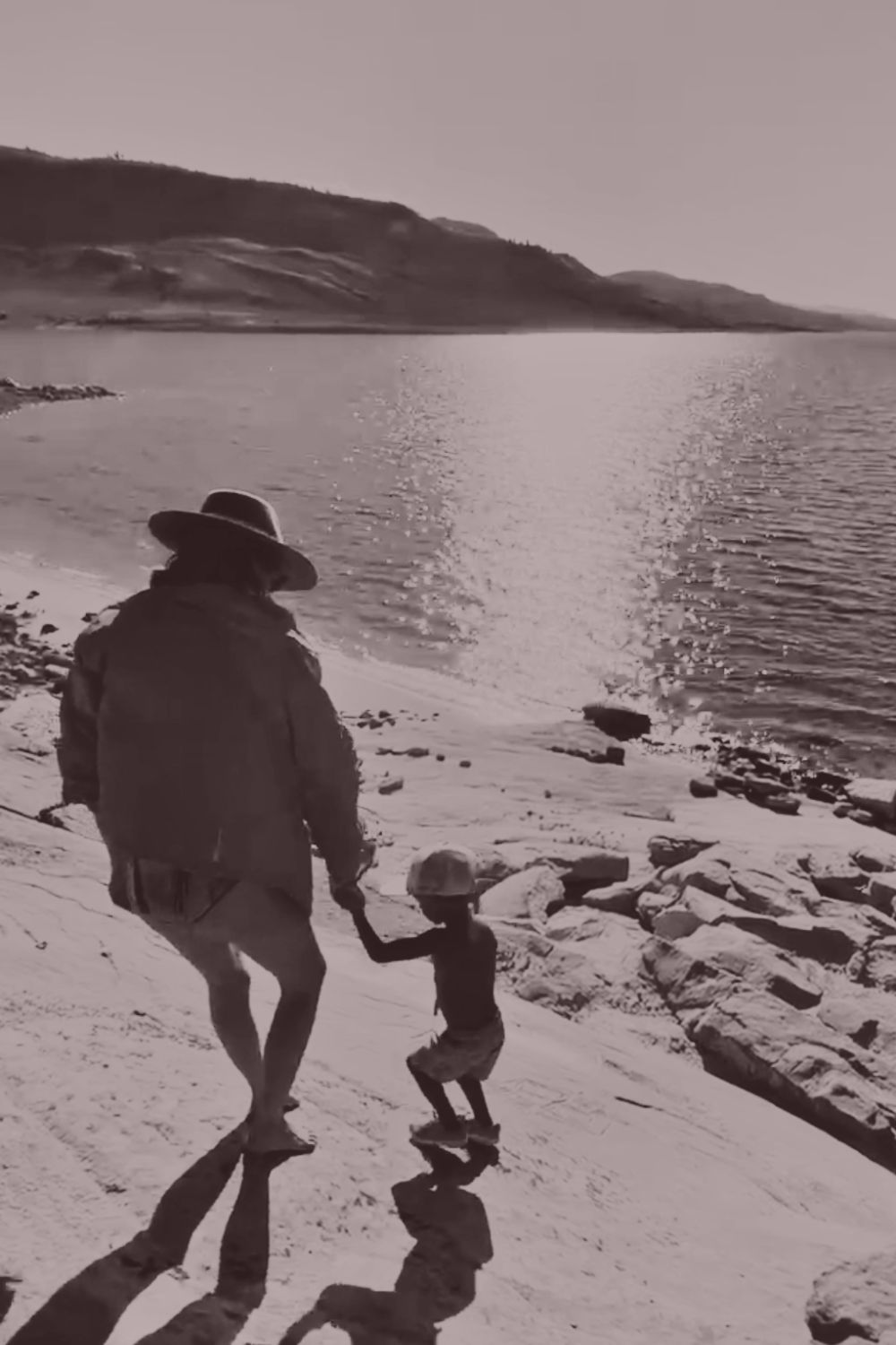 Rita walking hand in hand with her nephew along a lake shore