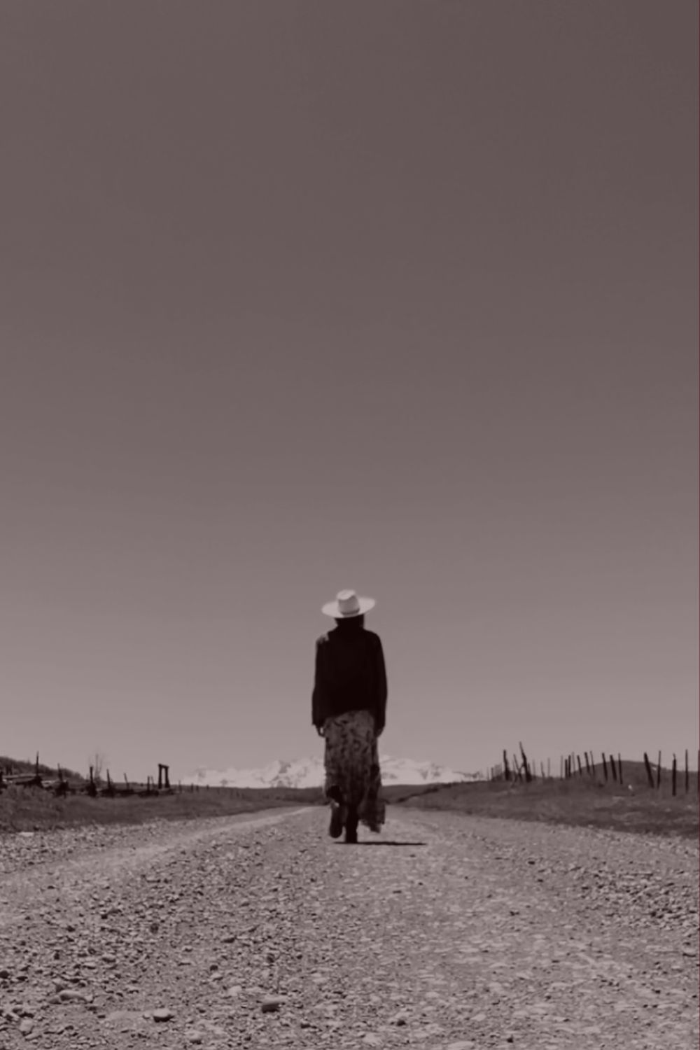 A woman walking a quiet road toward distant mountains